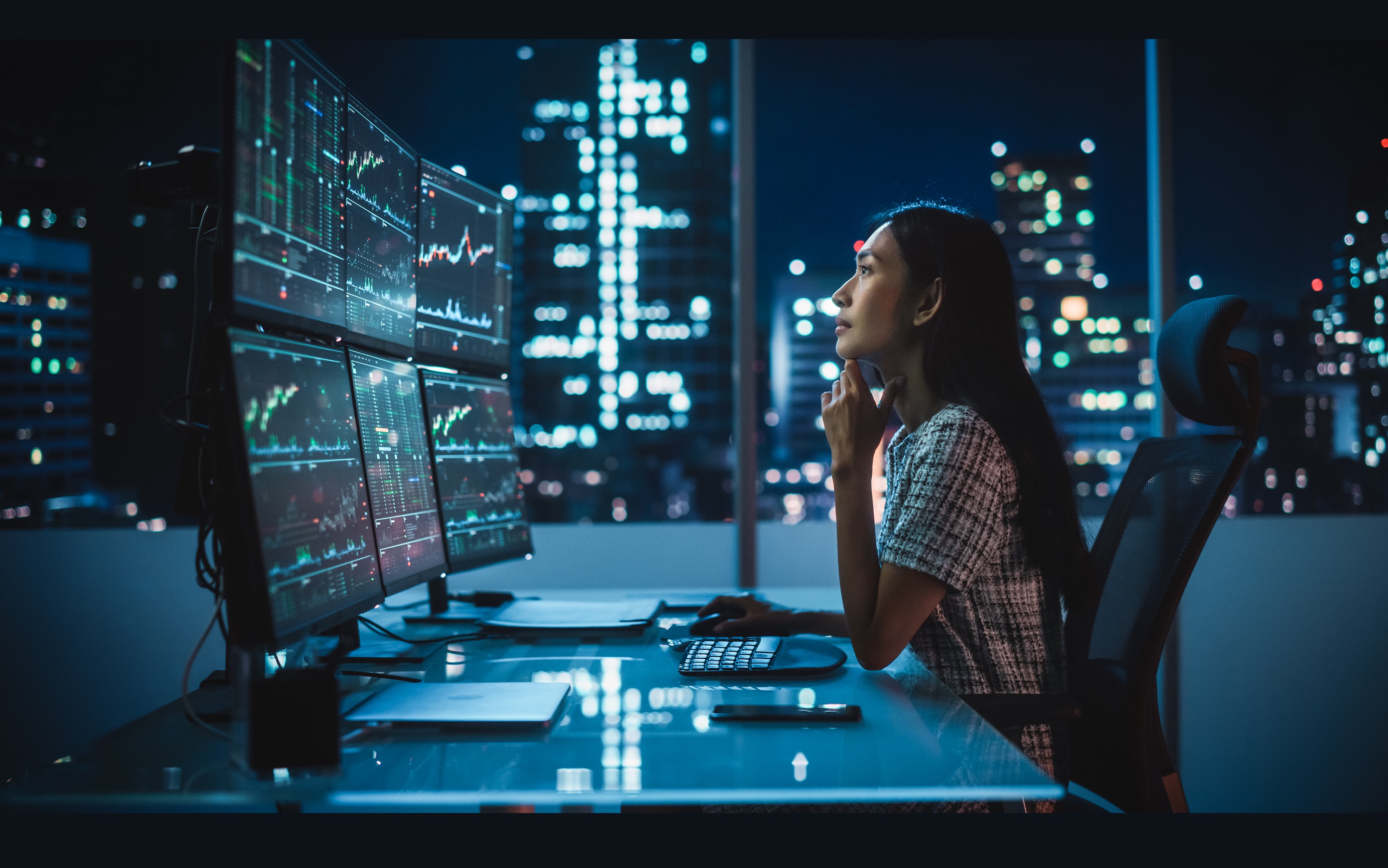 Portrait of a Financial Analyst Working on Computer with Multi-Monitor Workstation with Real-Time Stocks, Commodities and Exchange Market Charts. Businesswoman at Work in Investment Broker Agency.