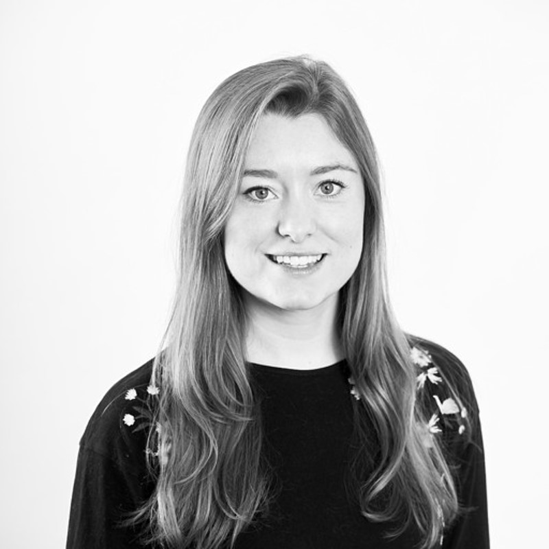 Person with long hair in a dark top with floral shoulder patterns and a blurred face.