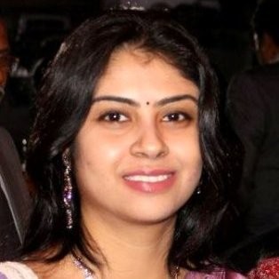 portrait of a person with dark hair and earrings against a dark background.