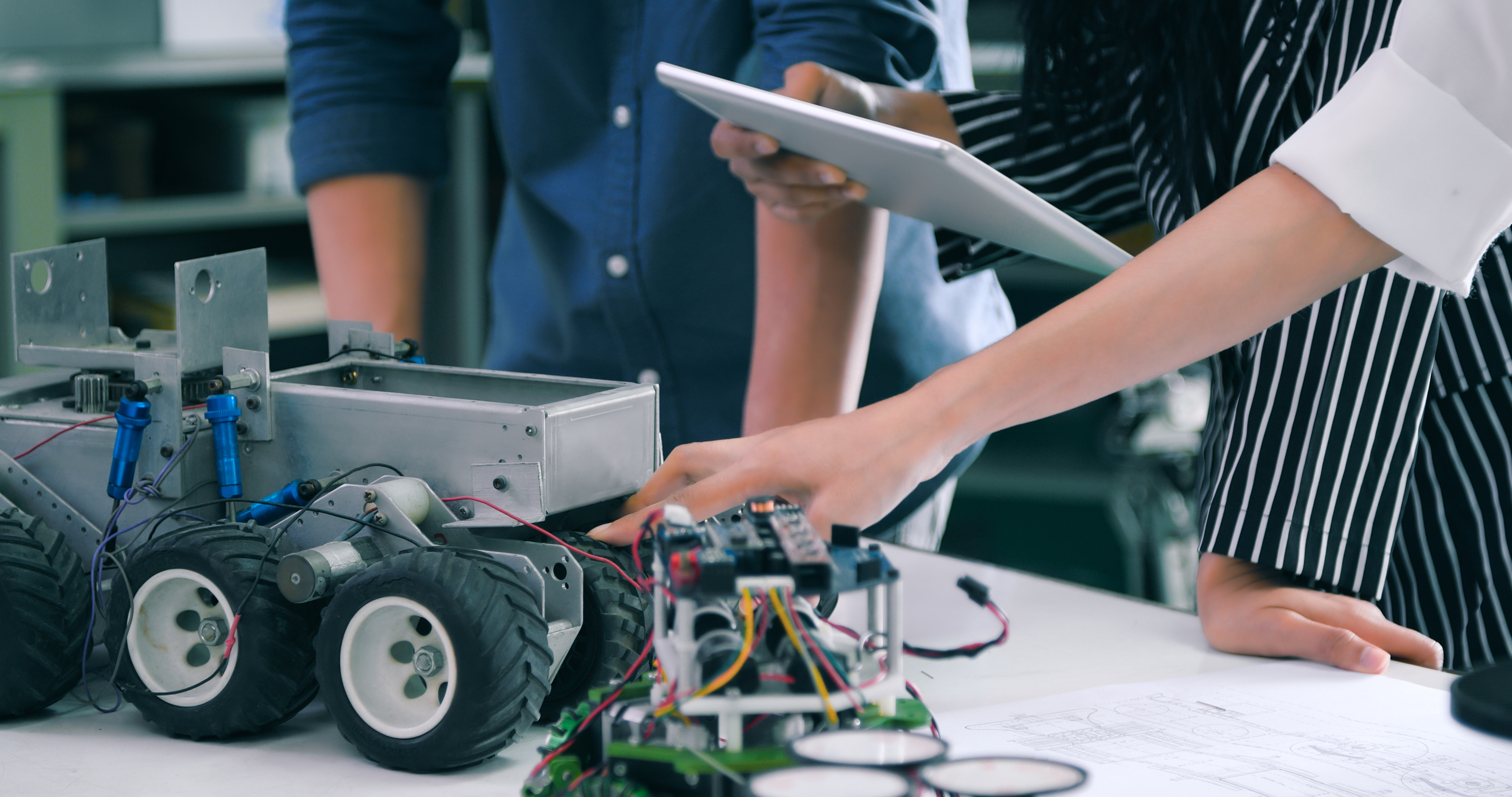 Engineering students work together to assemble and program a robot, showcasing teamwork and technical skills in a robotics lab.