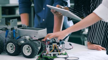 Engineering students work together to assemble and program a robot, showcasing teamwork and technical skills in a robotics lab.