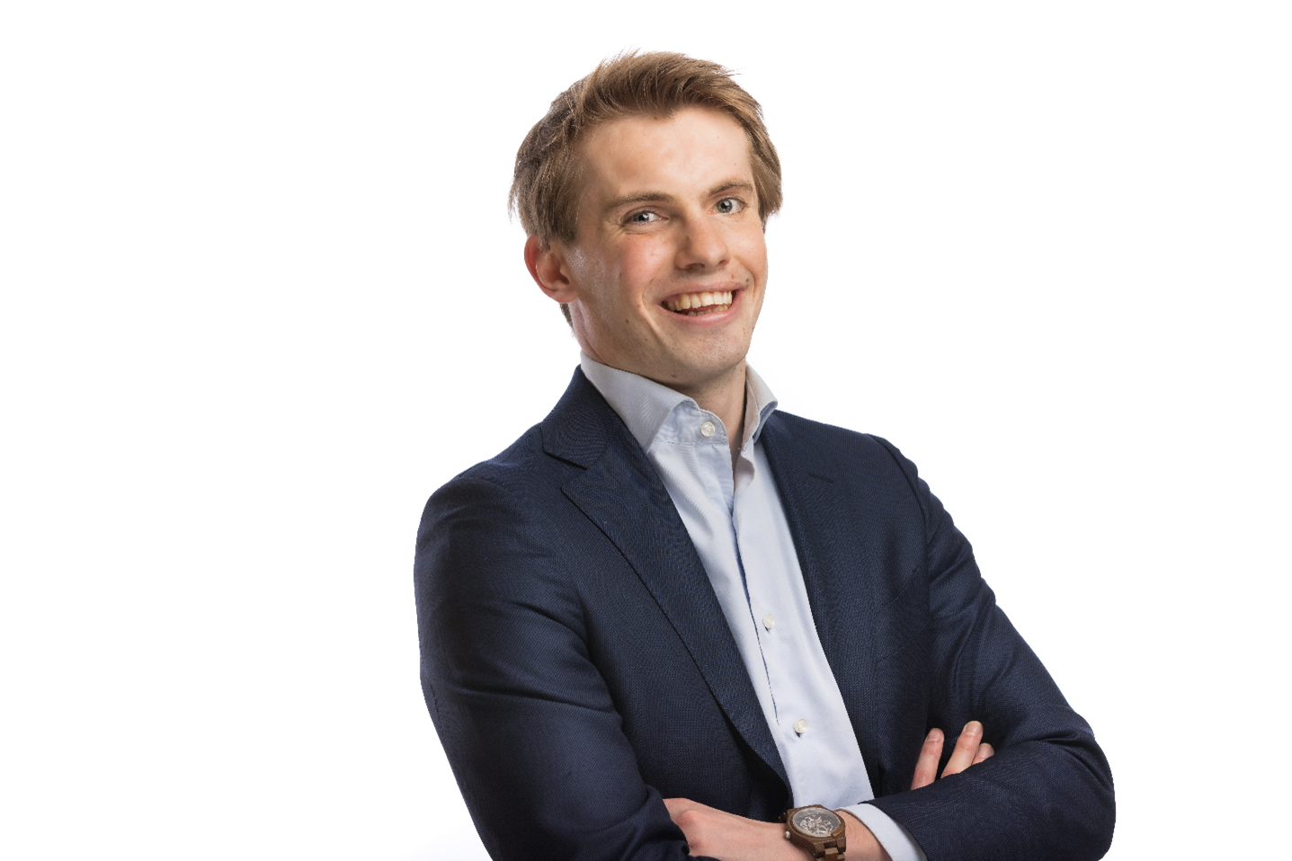 Person in a dark blue suit with a light blue shirt, arms crossed, wearing a wristwatch, and face blurred.