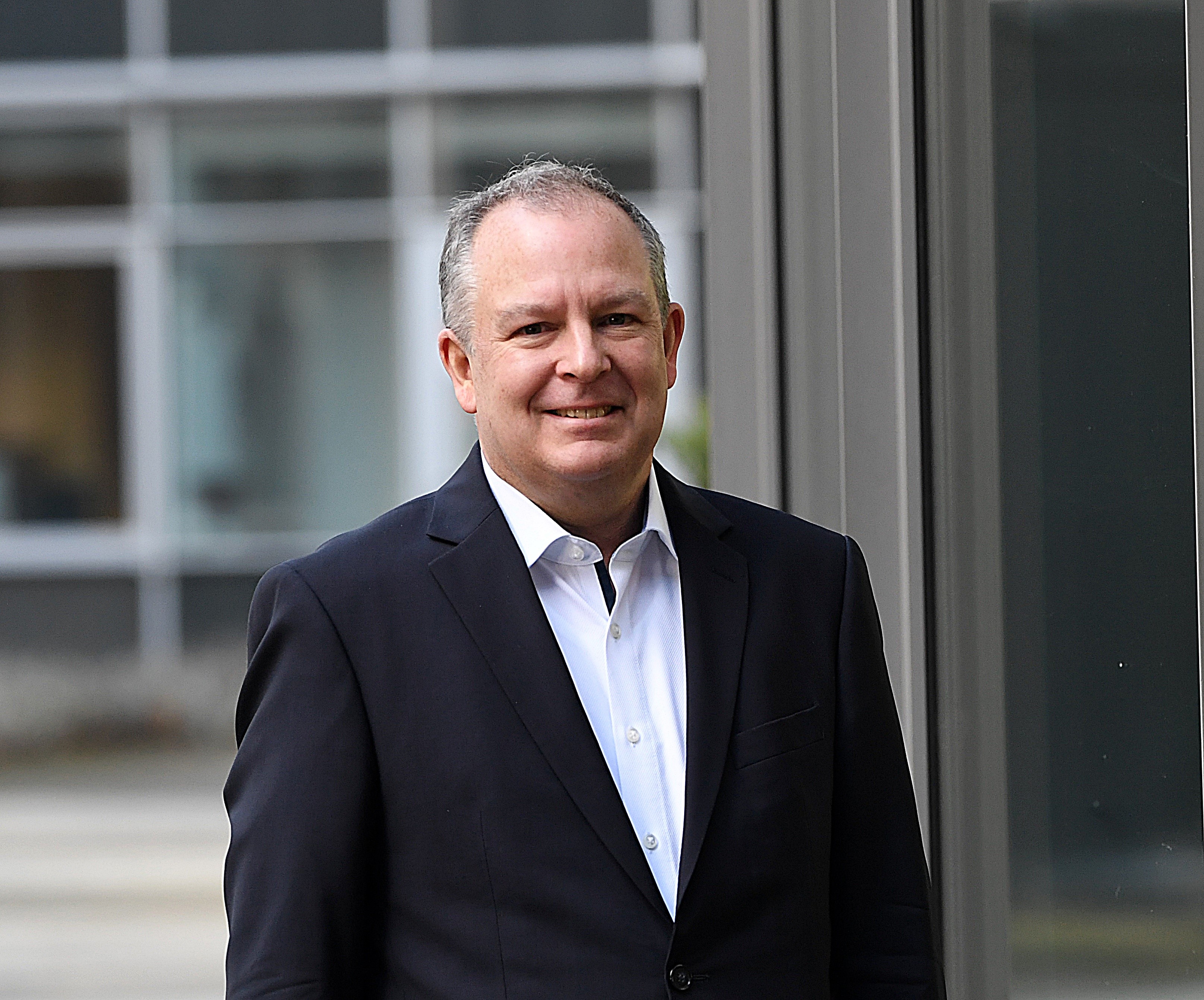 Portrait of Karl Heinz Krug with backdrop highlighting public finance and technology integration.